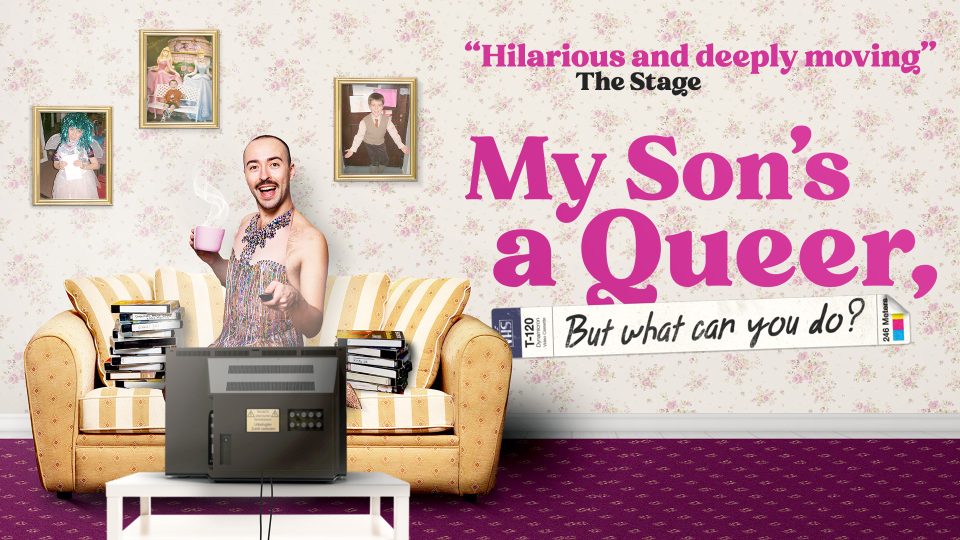 A man in a sparkly dress holding a pink mug, surrounded by family photos.