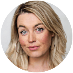 Smiling woman with blonde hair, hoop earrings, and light makeup against a plain white background.