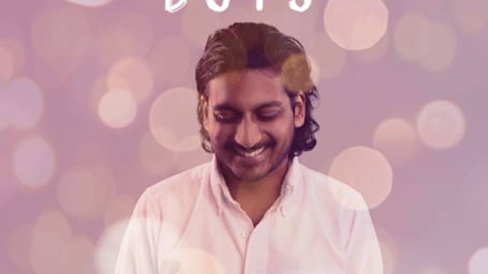 Ahir Shah smiling against a soft, blurred background with warm bokeh lights.