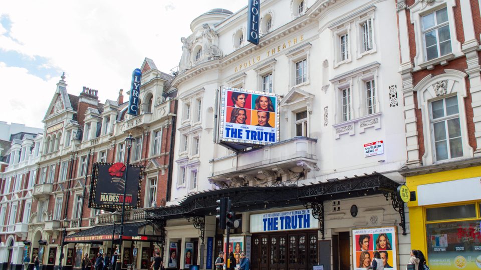 Apollo Theatre facade with "The Truth" posters, white ornate architecture, and blue signage.