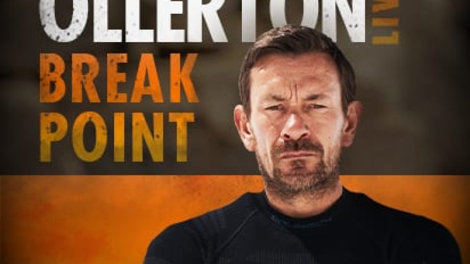 A serious man in a black outfit, with an orange and grey background promoting "Breakpoint.