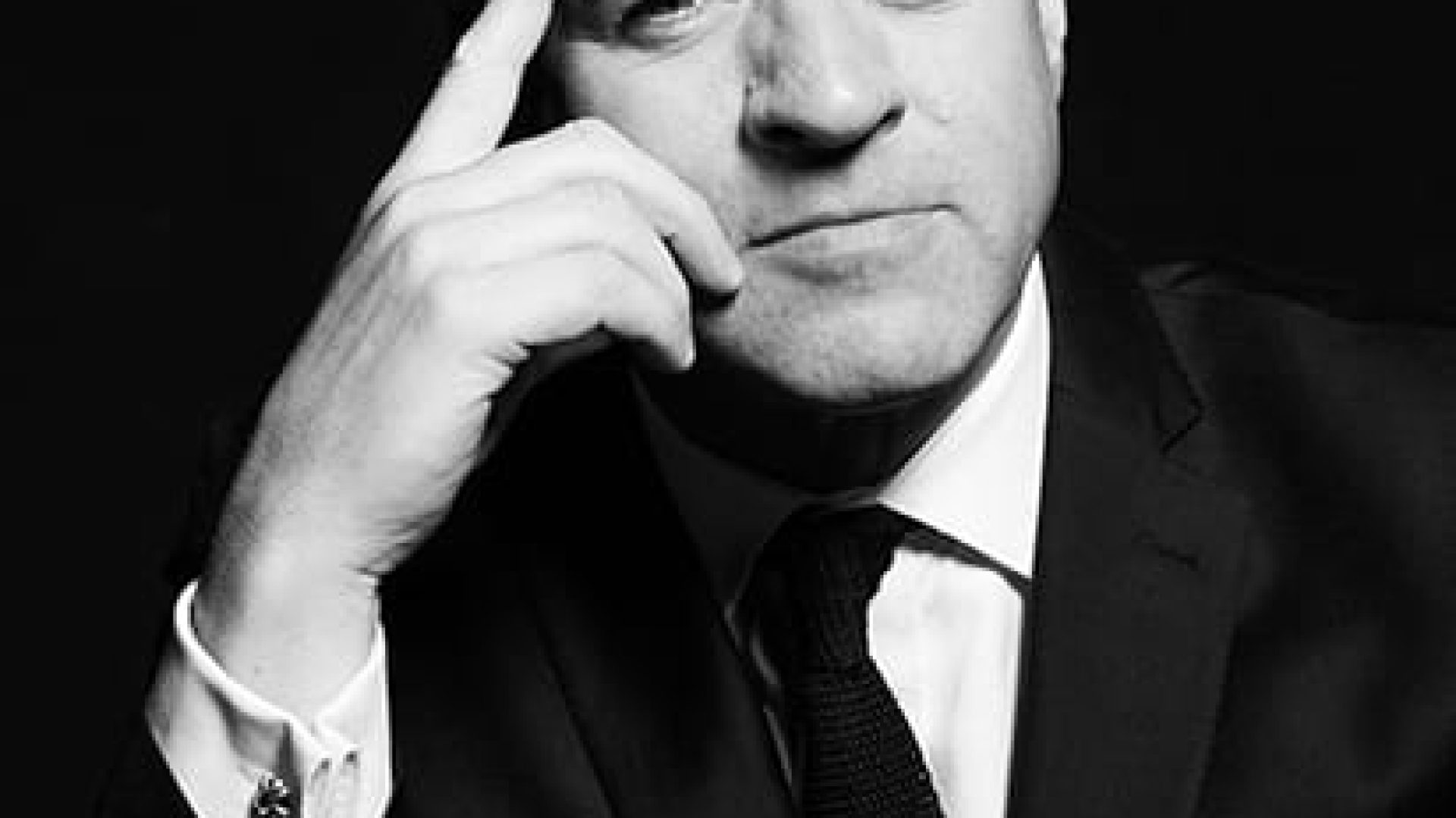 Black and white portrait of Niall Ferguson, dressed in a suit, with a serious expression.