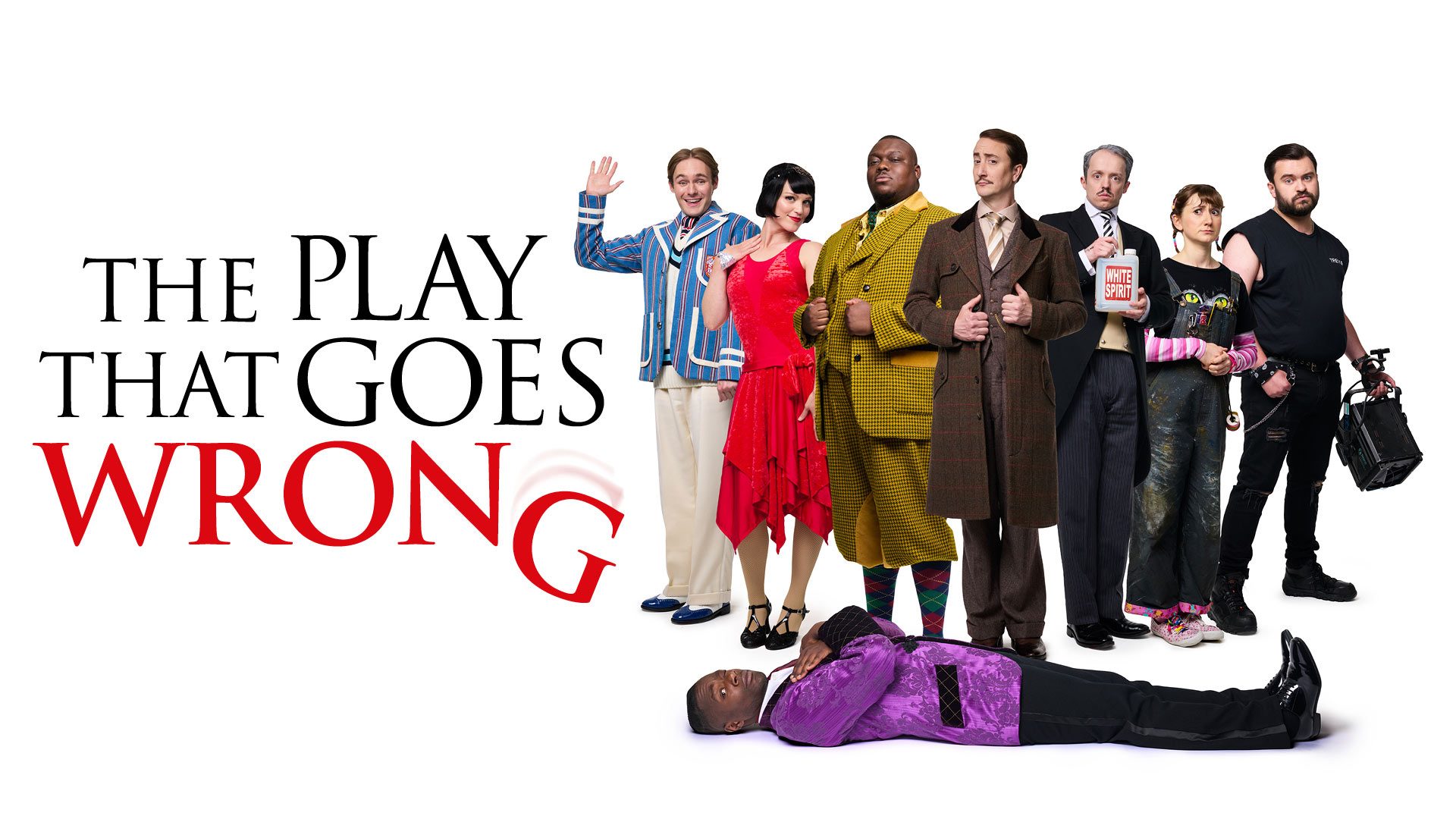 Six actors in colourful costumes pose comically; one lies on the floor in a purple jacket.