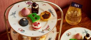 Afternoon tea with cakes and teapots, bright café setting.