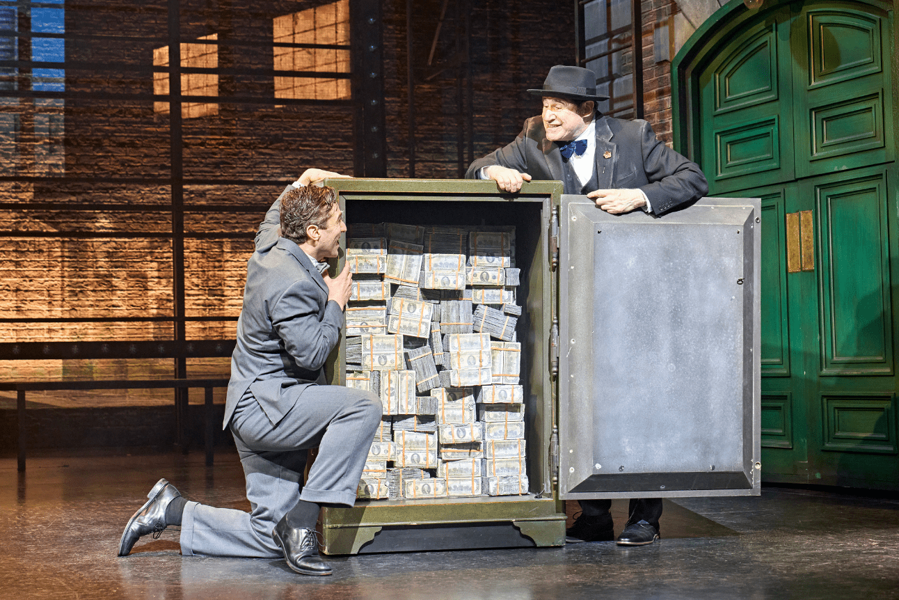 Max and Leo admire all the money that has been raised and piled high in the safe