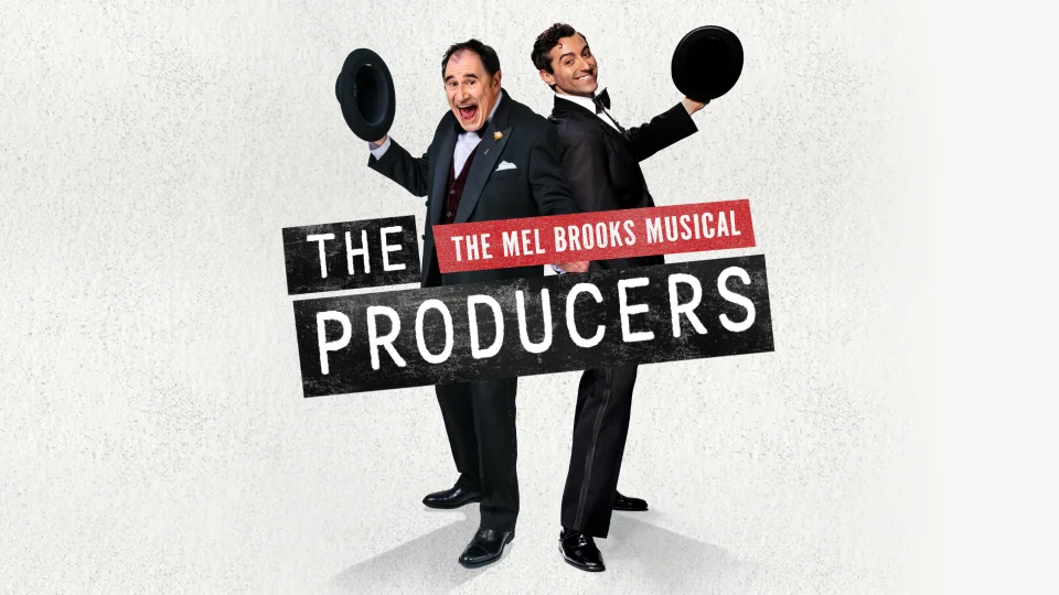 Richard Kind and Marc Antolin stand in tuxedos beaming with energy. On top of them is The Producers logo