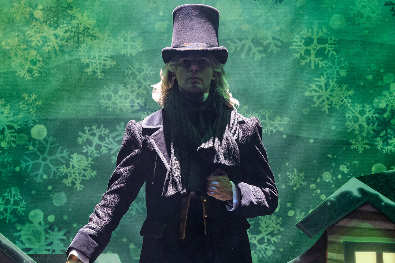 Daniel Fraser in period costume, mid-performance with expressive gesture against dark theatre backdrop.