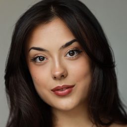 A woman with long dark hair and neutral expression against a grey background.