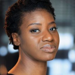 Carole Stennett looks towards the camera with a neutral expression, blurred background.