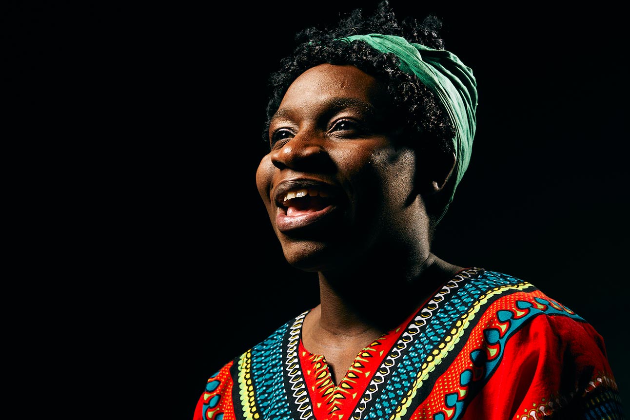 A smiling person in a vibrant red patterned shirt against a dark background.