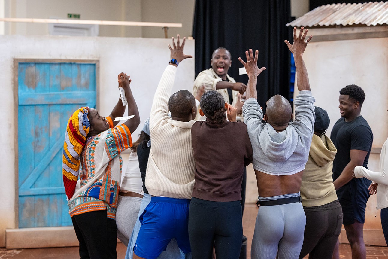 Actors in casual clothes raise their hands during a rehearsal for The Boy Who Harnessed the Wind.