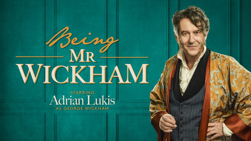 Adrian Lukis as Mr Wickham, wearing 19th-century attire, stands against a green, textured background.