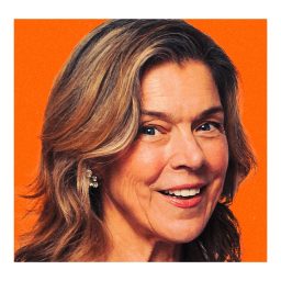 Janie Dee smiling against a plain orange background.