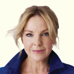 Sarah Hadland smiling, against a pale background