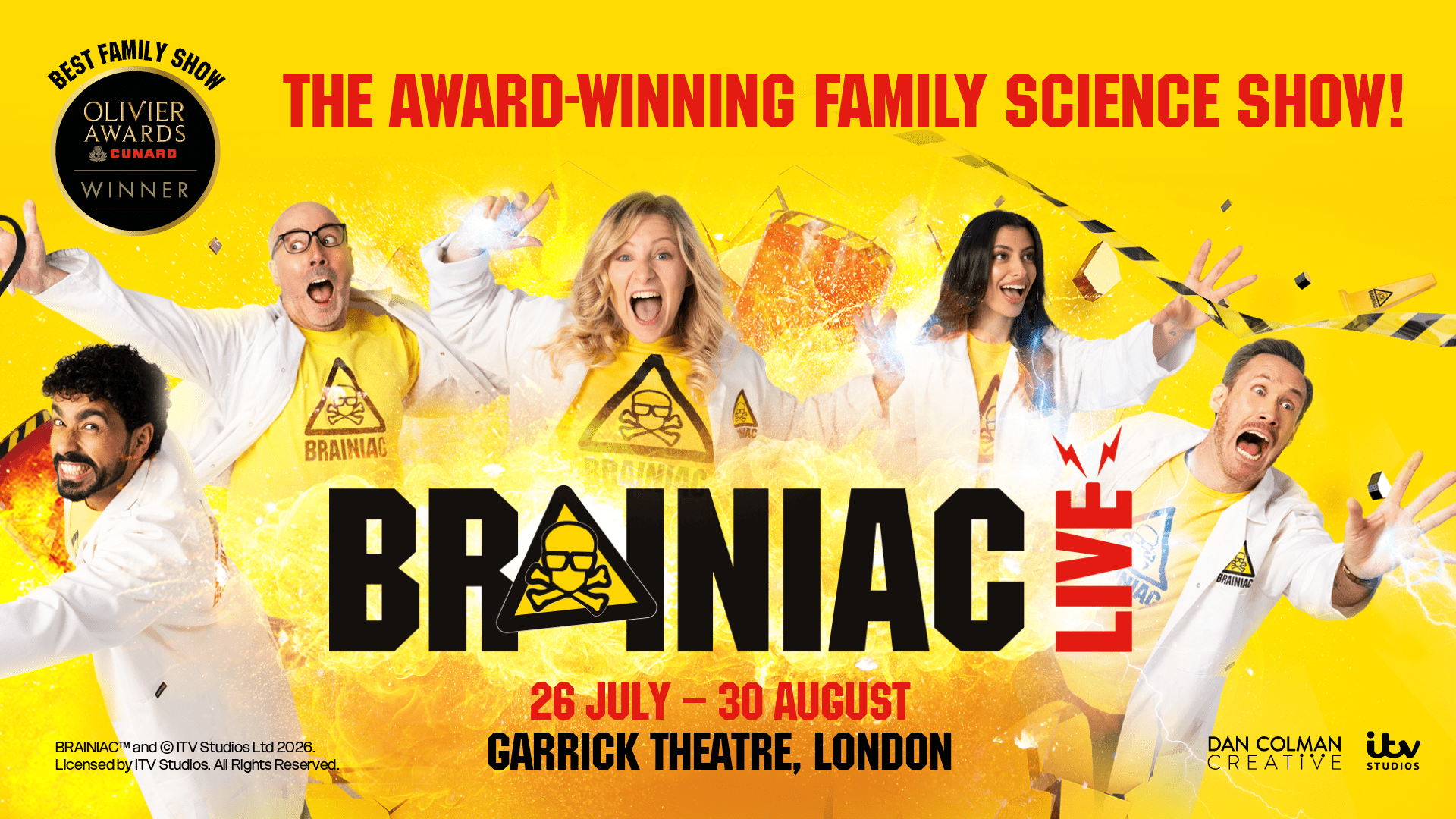 Four performers in lab coats, holding colourful science equipment, stand on stage with a vibrant backdrop.