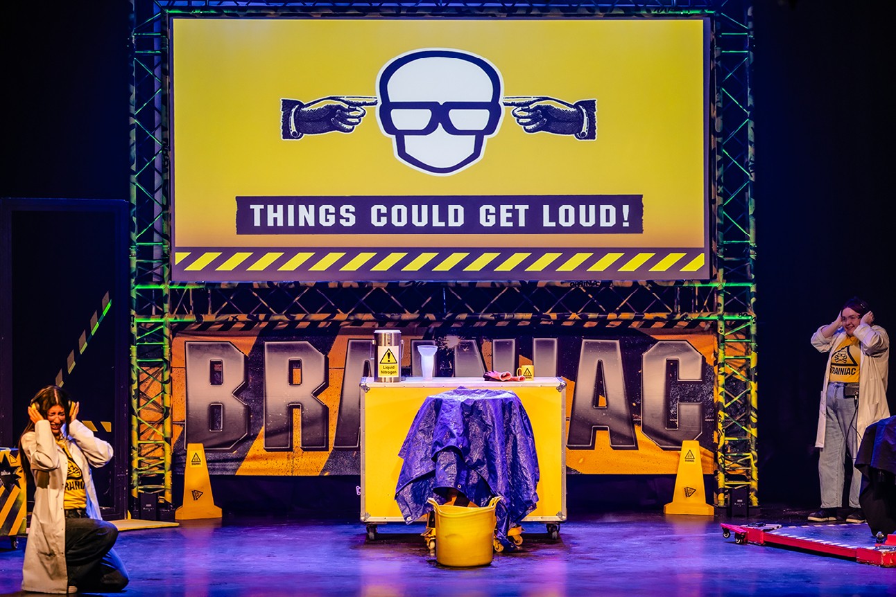 Stage setup with a yellow table, caution cones, and a sign reading "Things Could Get Loud!