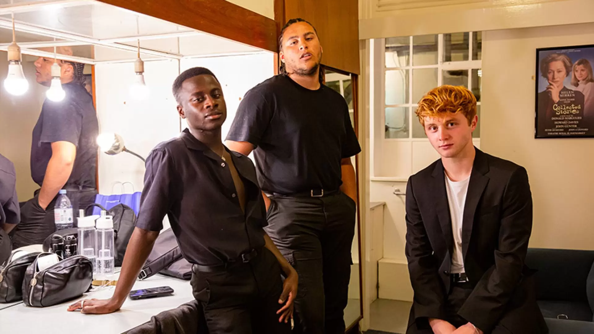 Two actors on stage, one in a red dress, the other in a black suit, dramatic lighting.