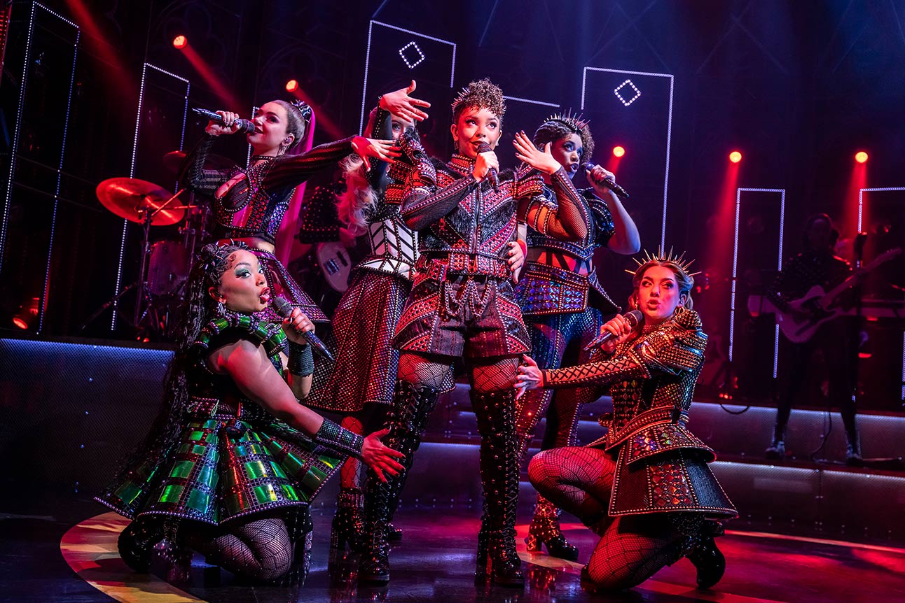 A smiling man in a blue suit and red tie stands against a plain white background.