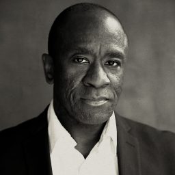 A man in a suit and white shirt, looking directly at the camera, neutral expression.