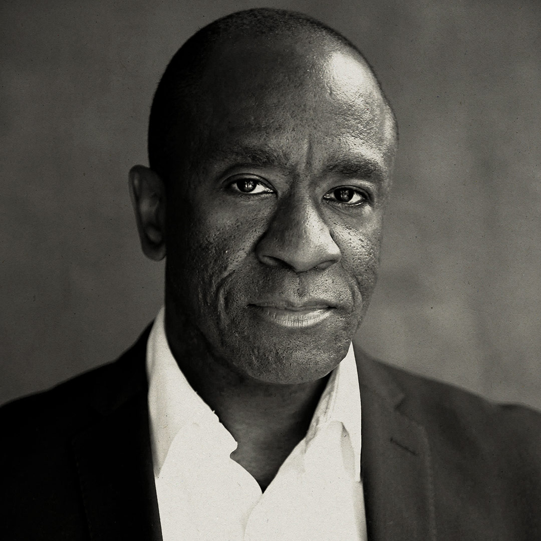 A man in a suit and white shirt, looking directly at the camera, neutral expression.