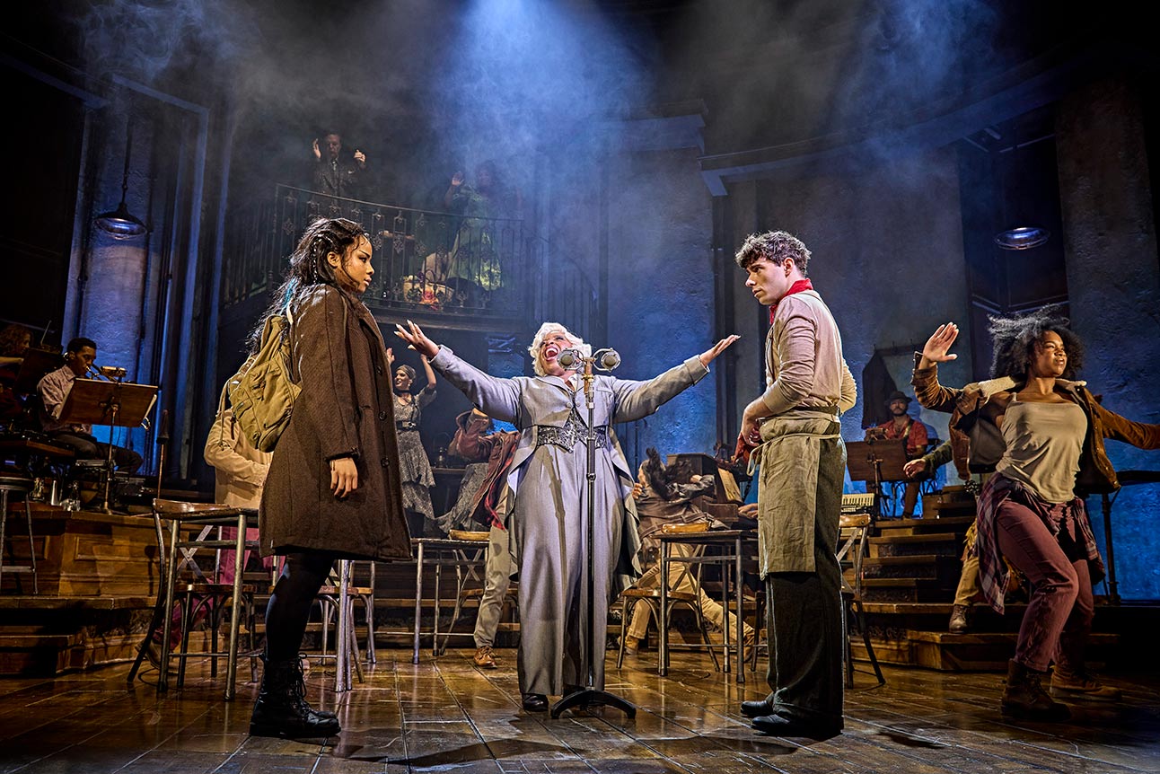 Fayth Ifil, Malinda Parris, and Nathan Sykes perform on stage in Hadestown, dramatic lighting above.