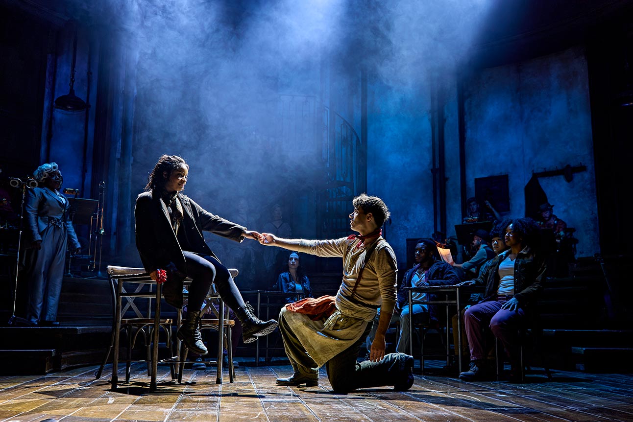 Fayth Ifil and Nathan Sykes perform on stage in Hadestown, with dramatic blue lighting.