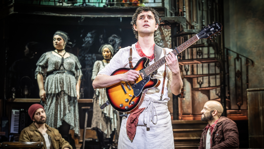 Orpheus plays the guitar in front of a packed stage