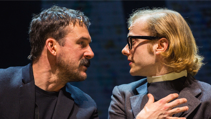 A man stares intensely at a vicar with a look of menace