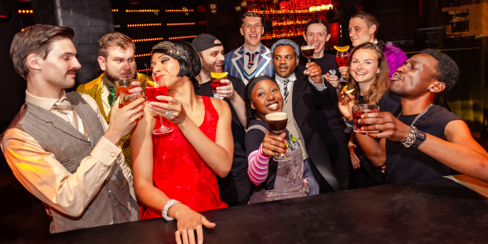 The Play That Goes Wrong cast cheersing their cocktails